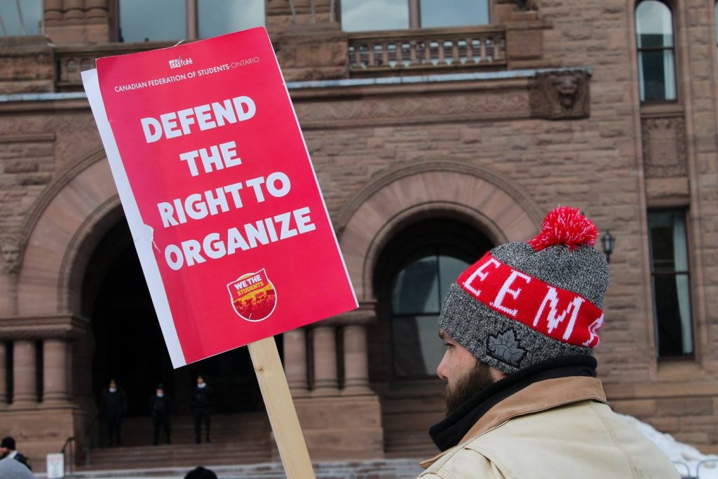 Person holding Protest sign against Fords STudent Choice initative 