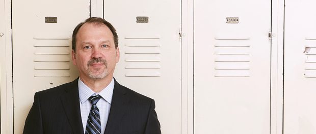 Photo of Harvey Bischof standing in front of lockers at Dunbarton High School